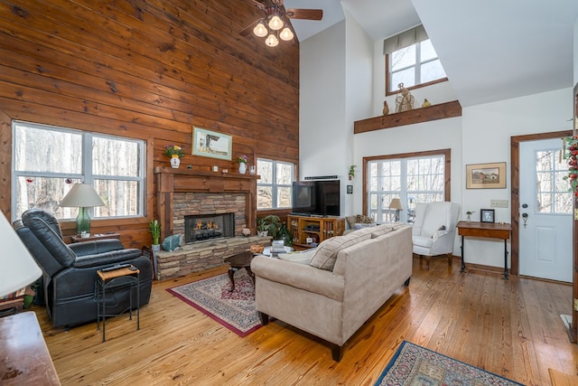 living room featuring a towering ceiling, a healthy amount of sunlight, a fireplace, and hardwood / wood-style floors