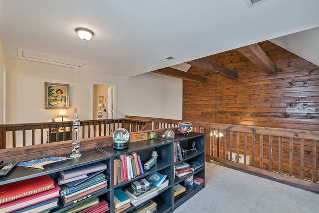 interior space featuring beamed ceiling, wooden walls, and carpet