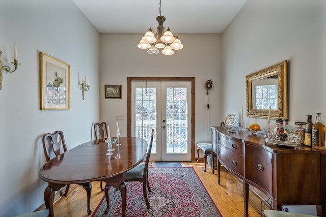 dining area with an inviting chandelier, french doors, and light wood-type flooring