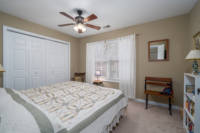 bedroom with ceiling fan, a closet, and light carpet