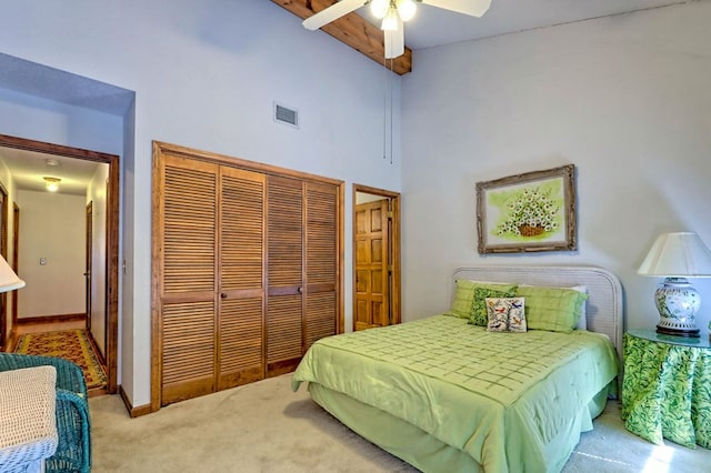 carpeted bedroom with ceiling fan, a towering ceiling, beam ceiling, and a closet