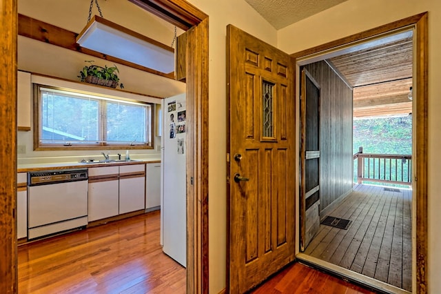 hall featuring sink, light hardwood / wood-style flooring, and a textured ceiling