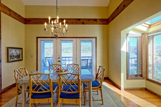 dining space featuring an inviting chandelier, light hardwood / wood-style floors, and french doors