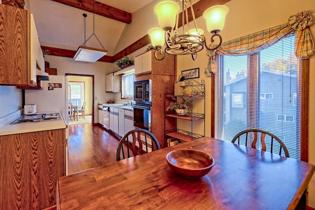 dining room with dark hardwood / wood-style flooring, vaulted ceiling with beams, and a chandelier