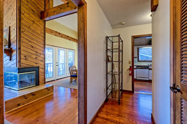 hall featuring wood-type flooring, french doors, a textured ceiling, and vaulted ceiling