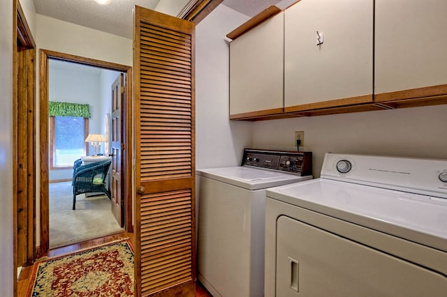 washroom featuring cabinets, a textured ceiling, and washer and clothes dryer