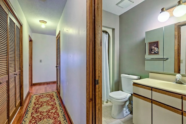 bathroom with vanity, hardwood / wood-style floors, a textured ceiling, and toilet