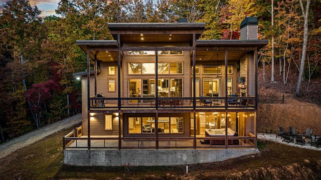 back house at dusk featuring covered porch