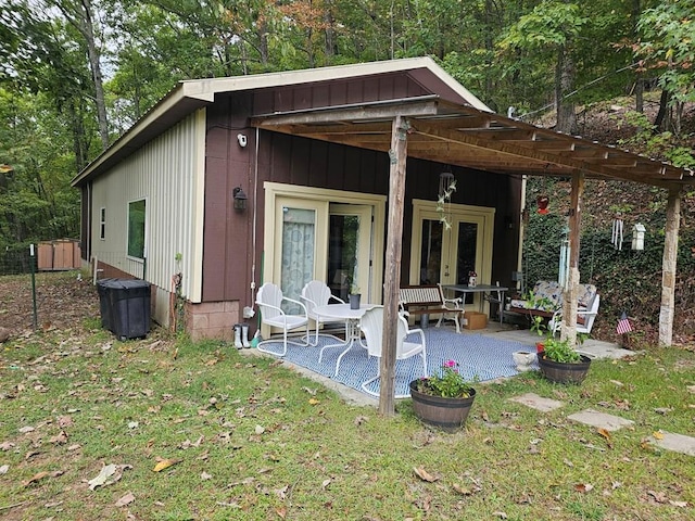 rear view of property featuring a patio, a lawn, and french doors