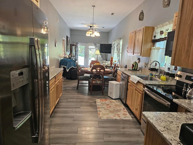 kitchen featuring appliances with stainless steel finishes, dark hardwood / wood-style floors, sink, a notable chandelier, and light stone countertops