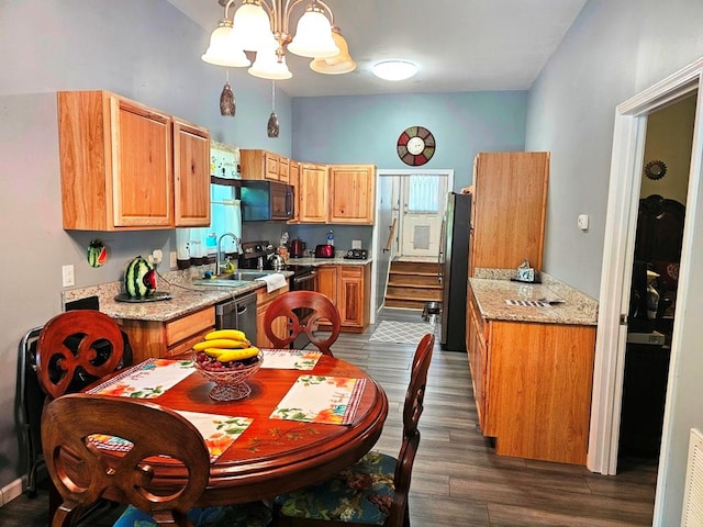 kitchen with sink, appliances with stainless steel finishes, dark hardwood / wood-style floors, light stone countertops, and decorative light fixtures