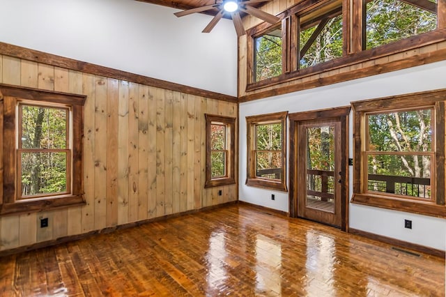 spare room with wood walls, high vaulted ceiling, hardwood / wood-style flooring, ceiling fan, and beam ceiling