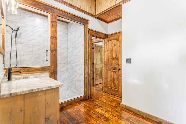 bathroom with hardwood / wood-style floors, vanity, and tiled shower