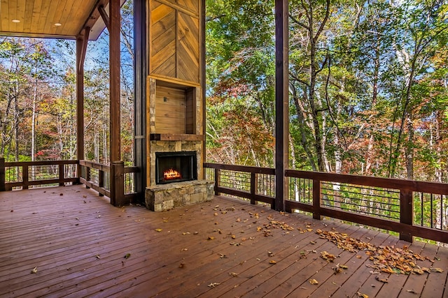 wooden terrace with an outdoor stone fireplace