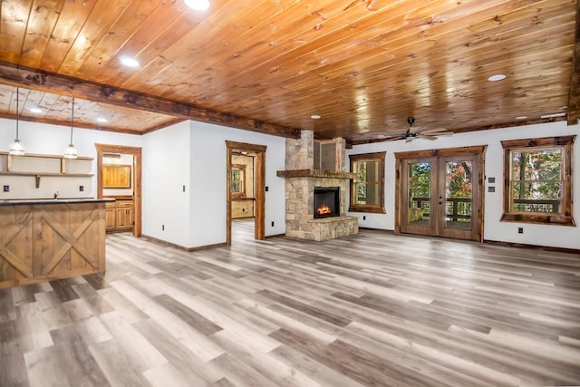 unfurnished living room featuring french doors, ceiling fan, wooden ceiling, a fireplace, and light hardwood / wood-style floors