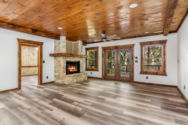 unfurnished living room with wooden ceiling, french doors, a stone fireplace, hardwood / wood-style flooring, and ceiling fan