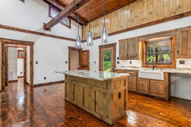 kitchen with hanging light fixtures, a kitchen island, plenty of natural light, and beamed ceiling