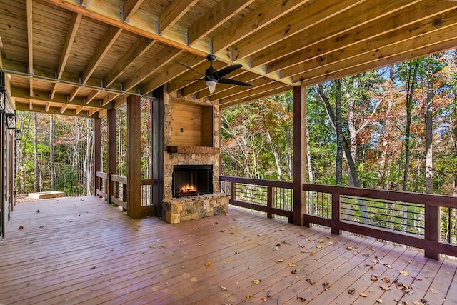 wooden deck featuring an outdoor stone fireplace and ceiling fan