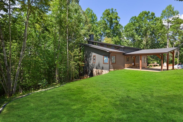 back of property with a carport and a lawn