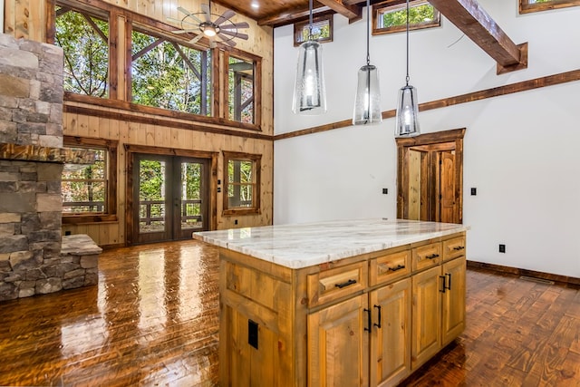 kitchen with pendant lighting, high vaulted ceiling, ceiling fan, a kitchen island, and beam ceiling