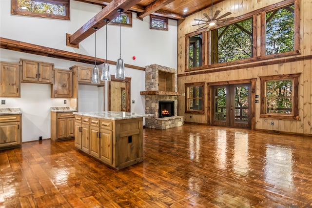 kitchen with light stone countertops, high vaulted ceiling, a healthy amount of sunlight, and a kitchen island