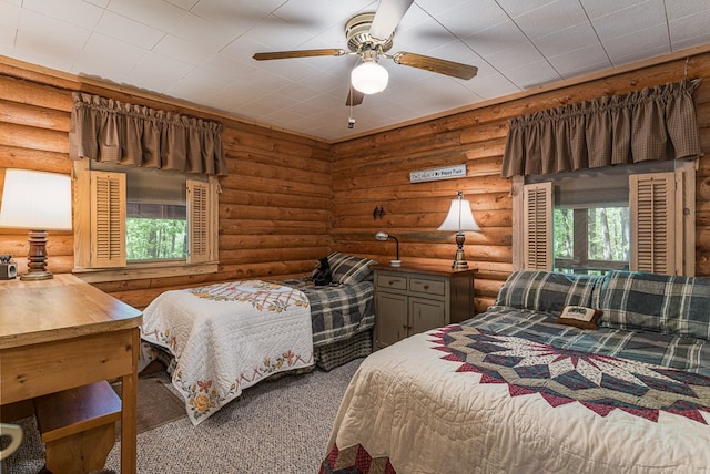 bedroom featuring carpet, rustic walls, and ceiling fan