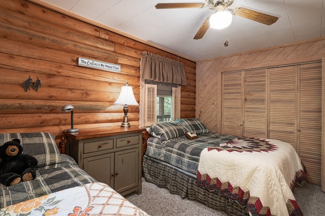 carpeted bedroom featuring a closet, a ceiling fan, and rustic walls