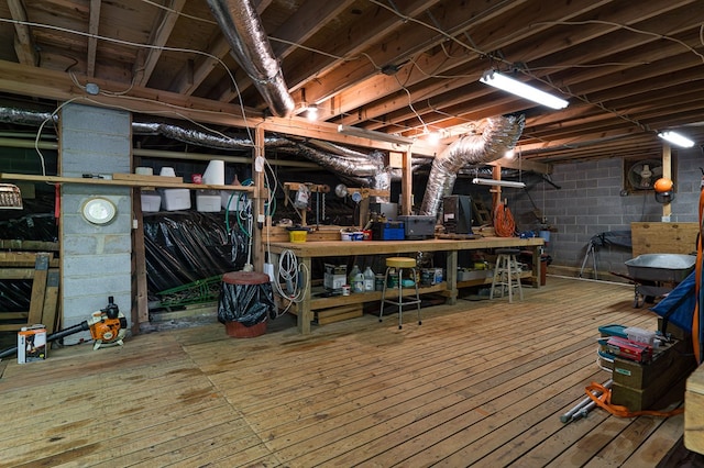 unfinished below grade area with concrete block wall, a workshop area, and hardwood / wood-style flooring