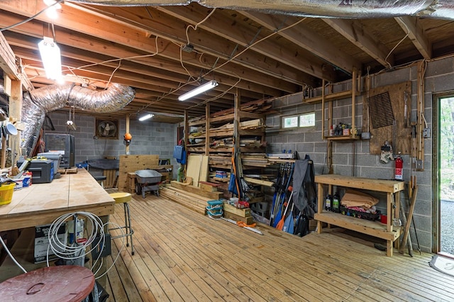 basement with concrete block wall, a workshop area, a healthy amount of sunlight, and hardwood / wood-style floors