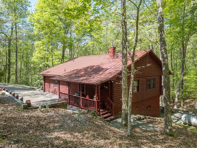 rear view of house featuring crawl space, a chimney, metal roof, and log siding