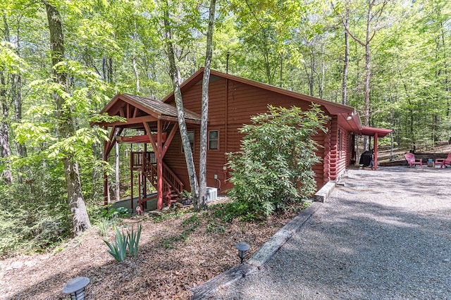 view of home's exterior with log siding, stairway, and a forest view