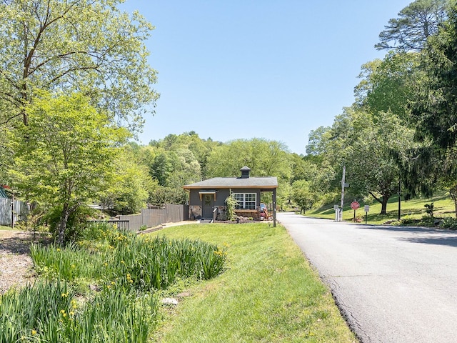 bungalow featuring fence, a chimney, and a front lawn