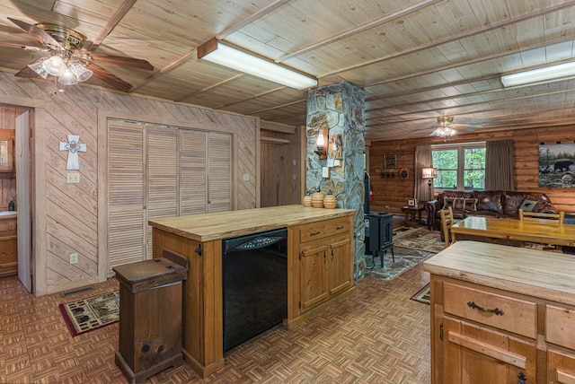 kitchen with ceiling fan, a wood stove, butcher block countertops, wood walls, and black dishwasher
