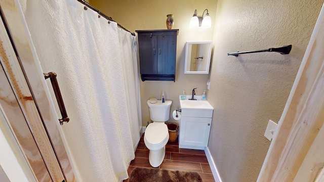 bathroom featuring toilet, wood tiled floor, baseboards, a textured wall, and vanity