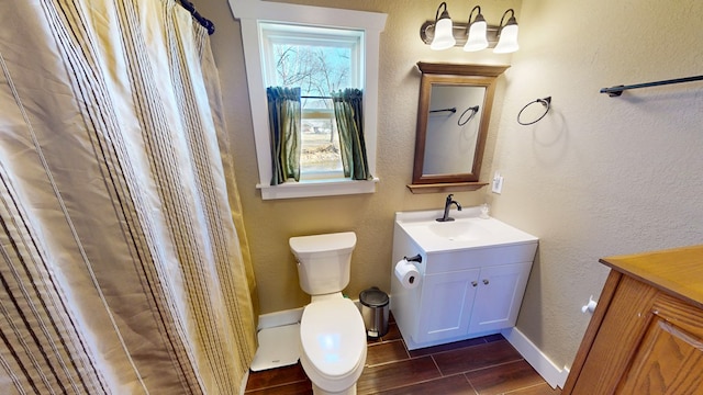 full bathroom featuring vanity, wood finish floors, baseboards, and toilet