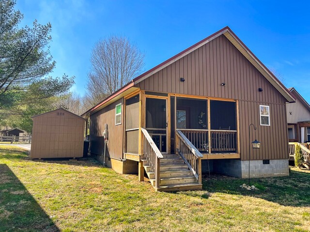 rear view of property with a yard, crawl space, a sunroom, and a storage unit