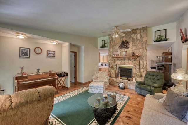 living area featuring a ceiling fan, a fireplace, and wood finished floors