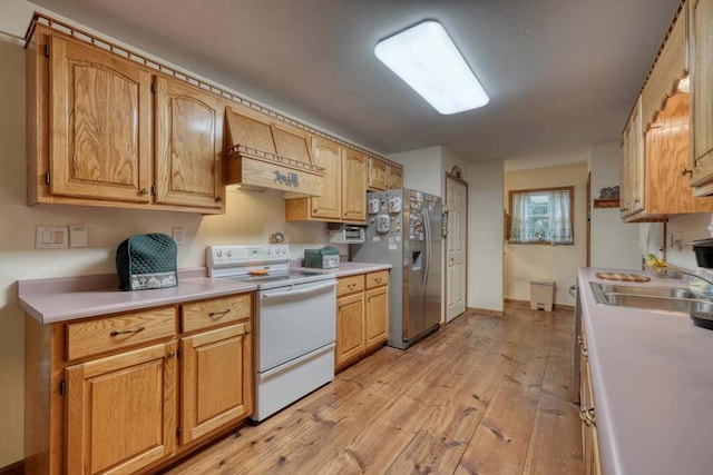 kitchen with custom exhaust hood, stainless steel fridge, sink, electric range, and light hardwood / wood-style floors