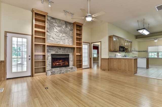 unfurnished living room featuring a stone fireplace, a ceiling fan, visible vents, and light wood finished floors