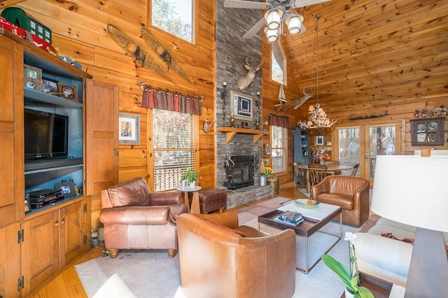 living room featuring wood walls, light hardwood / wood-style floors, a fireplace, and high vaulted ceiling