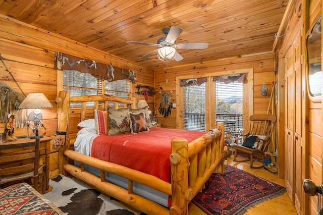 bedroom with access to exterior, light wood-type flooring, ceiling fan, wooden walls, and wooden ceiling