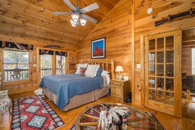 bedroom featuring light wood-type flooring, access to outside, vaulted ceiling, ceiling fan, and wood walls