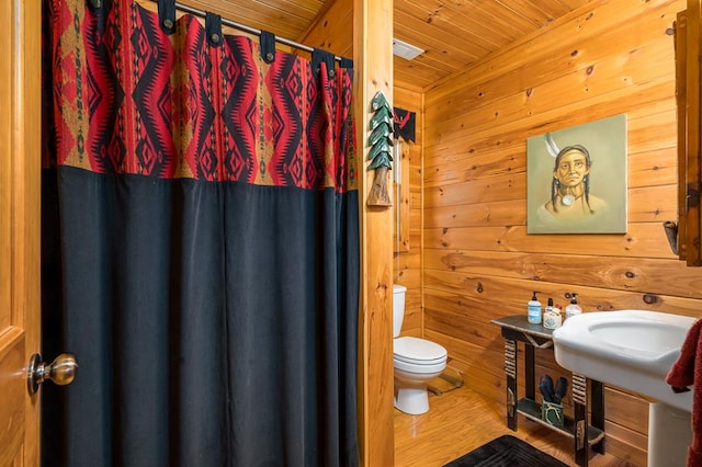 bathroom with a shower with curtain, wood walls, wood-type flooring, toilet, and wood ceiling