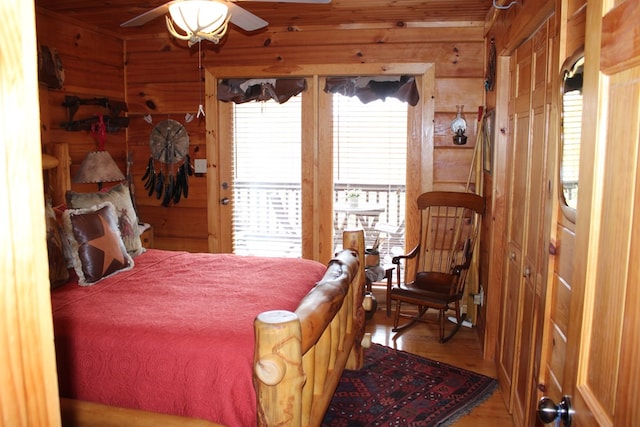 bedroom with wood walls, ceiling fan, and hardwood / wood-style flooring