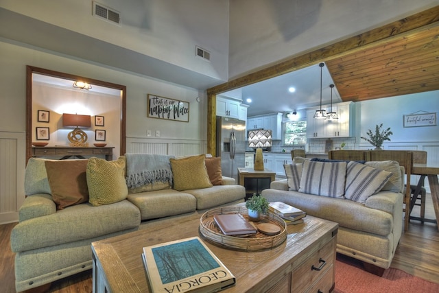 living area featuring a wainscoted wall, visible vents, and dark wood finished floors