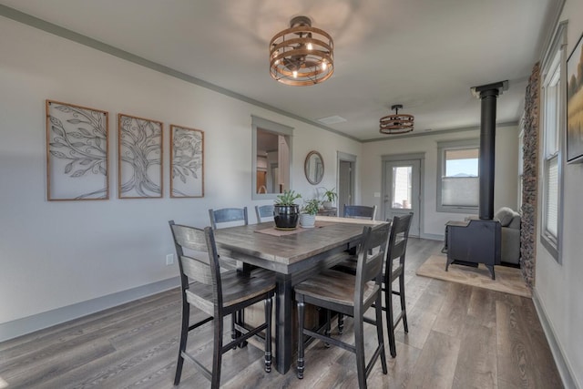 dining area with hardwood / wood-style flooring, ornamental molding, and a wood stove