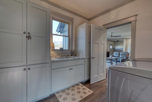 kitchen with washer / clothes dryer, sink, white cabinets, dark hardwood / wood-style flooring, and light stone countertops