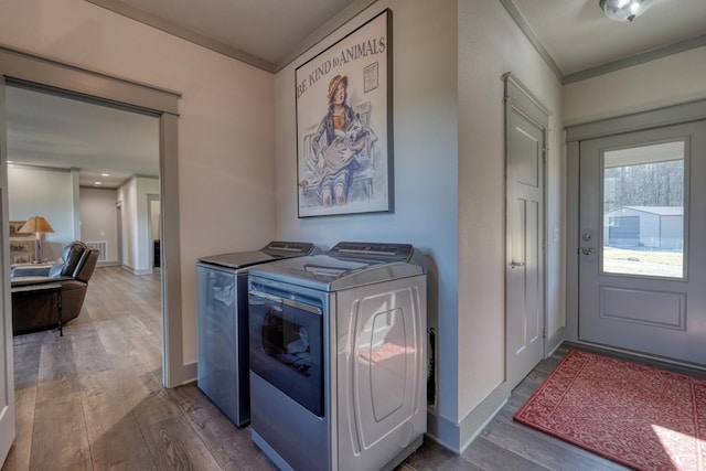 clothes washing area featuring hardwood / wood-style flooring, ornamental molding, and washer and dryer