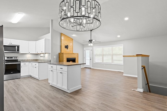 kitchen with baseboards, open floor plan, a large fireplace, a ceiling fan, and stainless steel appliances