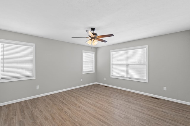 unfurnished room with baseboards, ceiling fan, visible vents, and wood finished floors